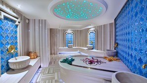 A luxurious bathroom with a marble floor, a central round mirror, and a blue patterned wall. - Beethoven Premium Hotel (Istanbul)