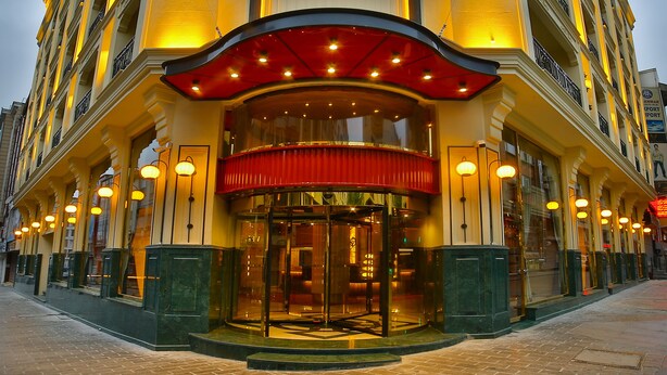 A hotel entrance with a glass door, a red awning, and multiple light fixtures. - Beethoven Premium Hotel (Istanbul)