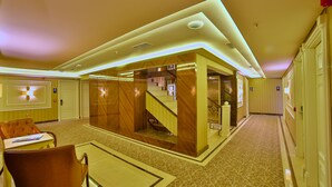 A hotel lobby with a modern design, featuring a central staircase, seating area, and a reception desk. - Beethoven Premium Hotel (Istanbul)