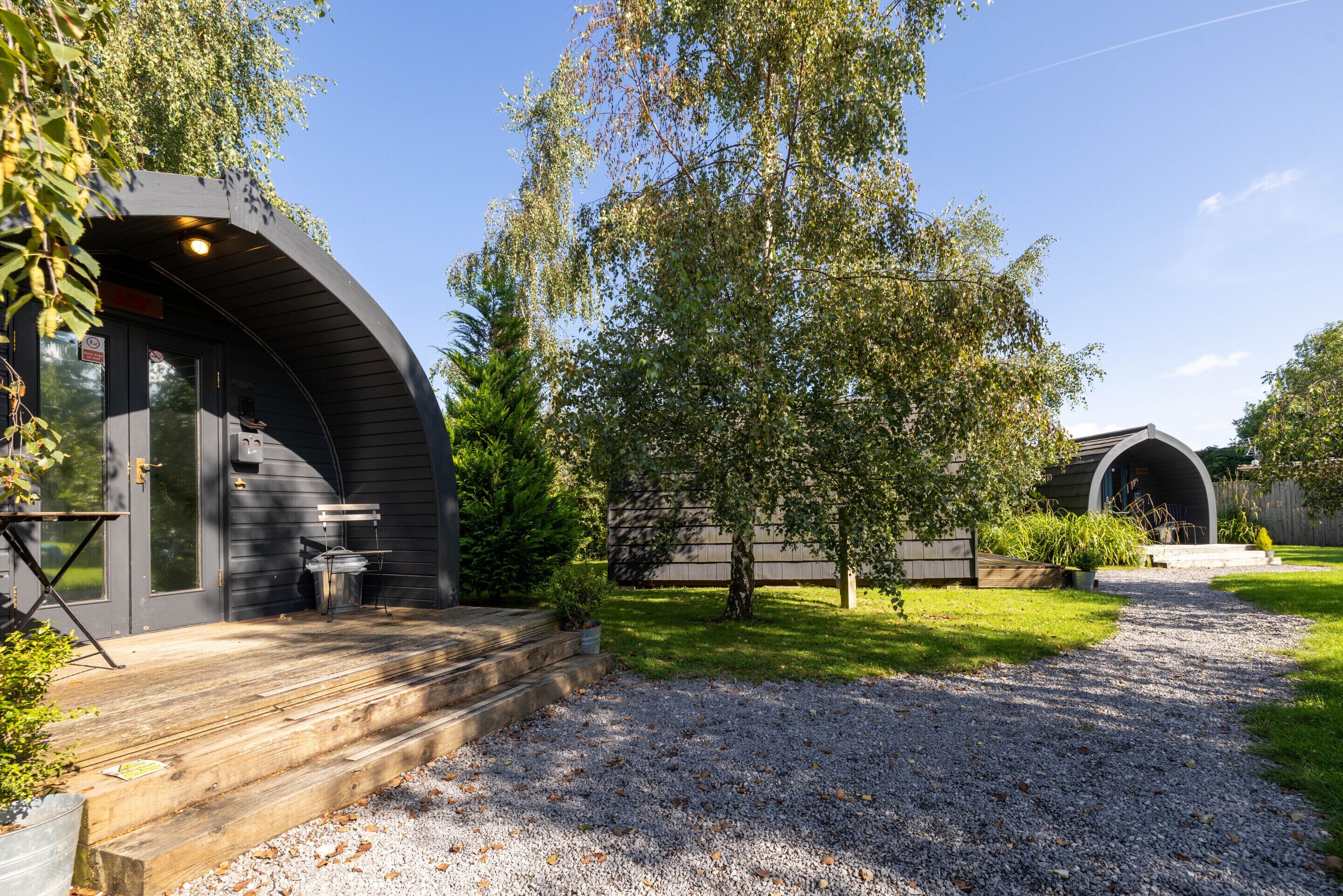 Een moderne chalet met een gebogen buitenkant, een grindpad en een verzorgd gazon.