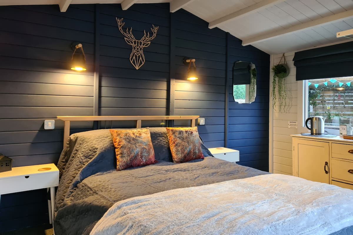 Une chambre à coucher comprenant un lit, des tables de chevet, une commode et une fenêtre donnant sur un beau paysage.
