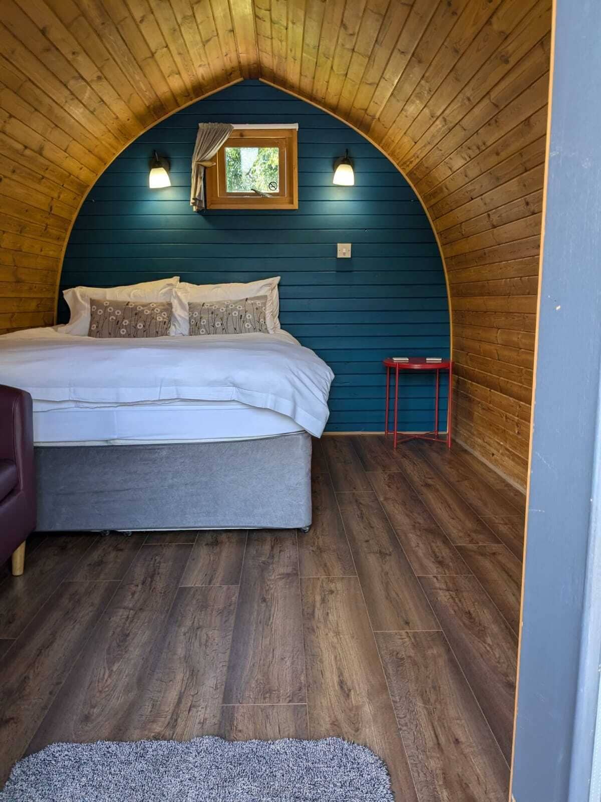 A cozy bedroom with a bed, a small window, and a red stool.