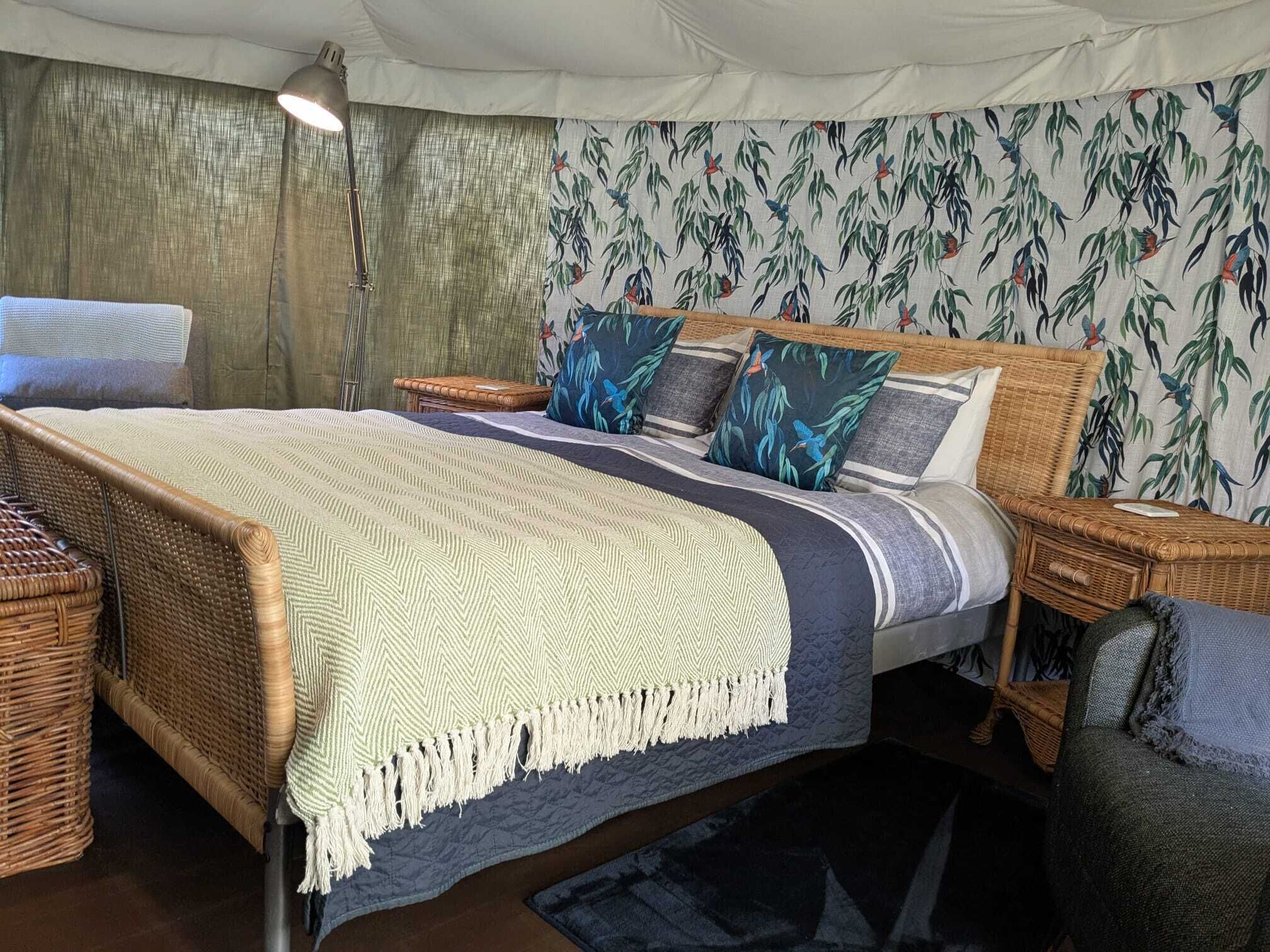 A bed with a herringbone-patterned bedspread, multiple pillows, and a woven headboard.