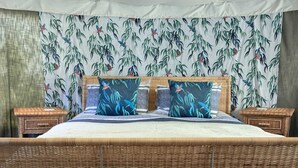 A bed with a canopy, a wicker side table, and a patterned wall. - The Little Hide - Adult Only Camping Pods (York)