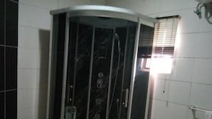 A bathroom with a glass-enclosed shower, a toilet, and a bidet. - Crown Apartments Extended Stay Suites (Abuja)