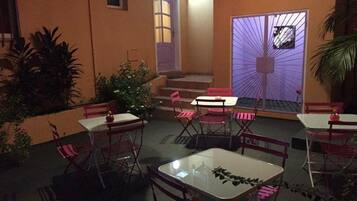 Un espace extérieur aménagé en terrasse, avec des tables et des chaises, un escalier et un mur décoratif.