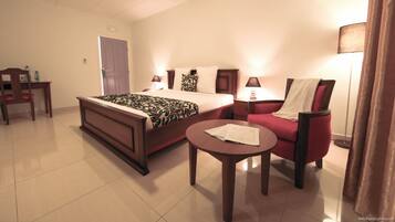 Habitación de hotel con cama, escritorio, silla, mesa redonda y lámpara.
