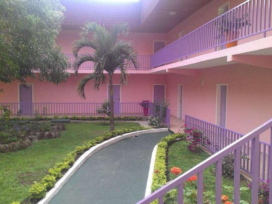 A multi-level building with a curved pathway, surrounded by greenery and a purple railing.
