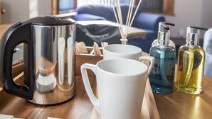 Una bandeja con una tetera, dos tazas blancas y dos frascos de perfume.