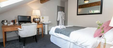 A bedroom with a desk, chair, bed, and a skylight.