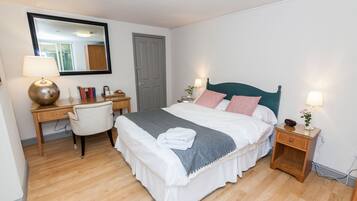 A neatly arranged bedroom with a bed, bedside tables, a desk, and a chair.