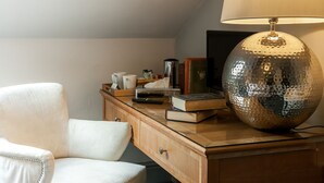 Un escritorio de madera con una lámpara, libros y un control remoto.