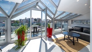 A modern living room with large windows, a red planter, a sofa, and a small table. - Juno Hotel Taksim (Istanbul)