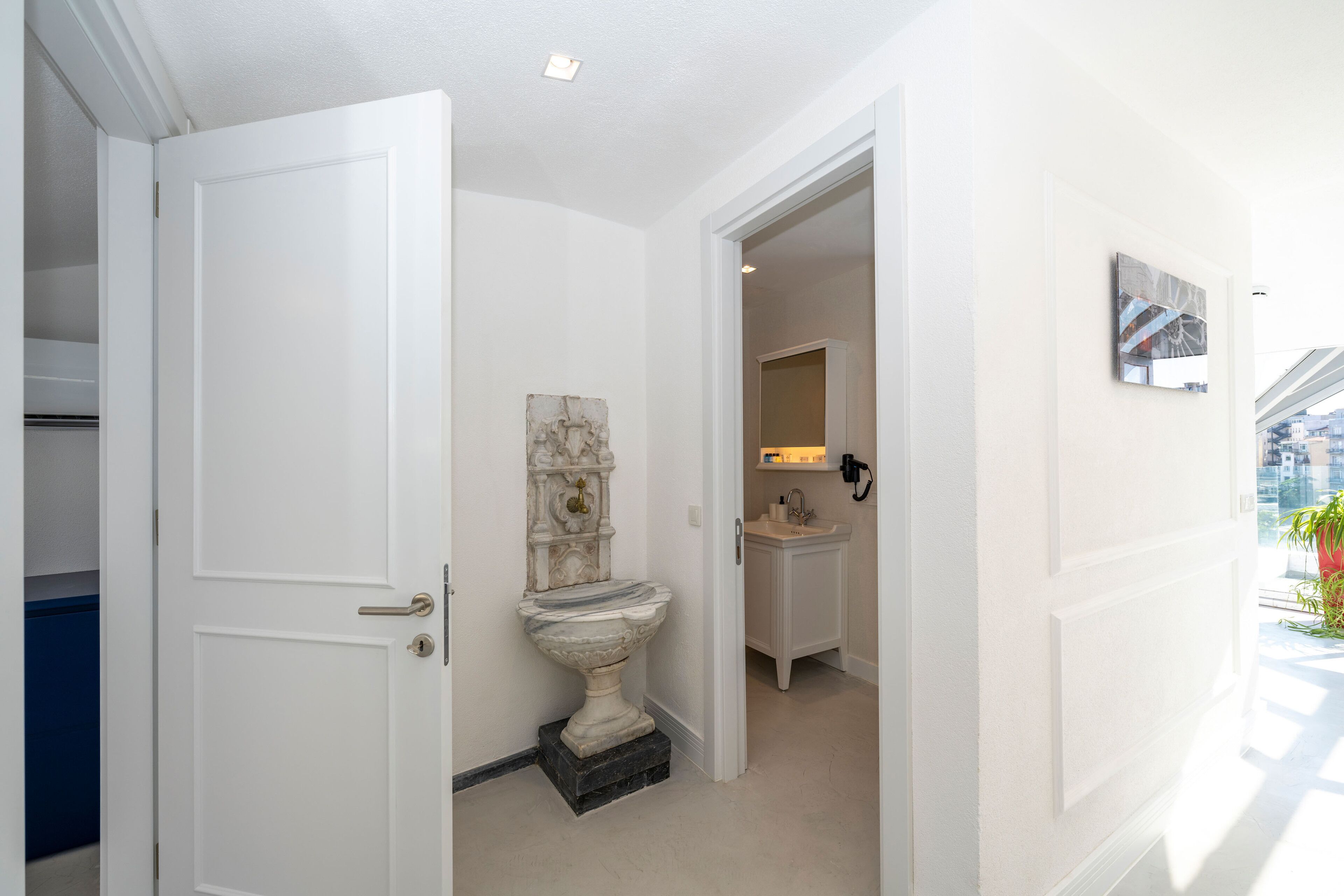 A bathroom with a pedestal sink, a toilet, and a mirror.