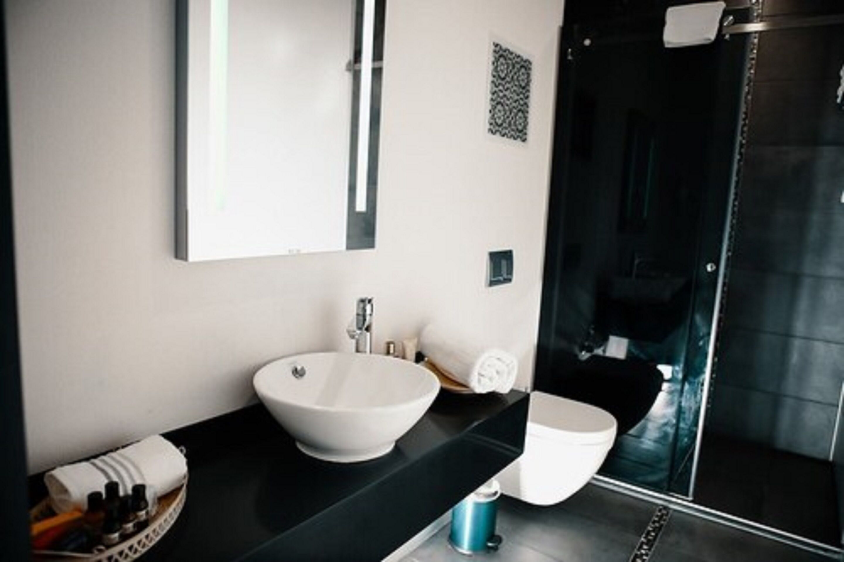 A modern bathroom with a large white sink, a toilet, and a glass-enclosed shower.