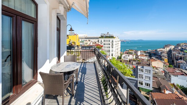 A balcony with wicker furniture and a view of the city and sea. - Juno Hotel Taksim (Istanbul)