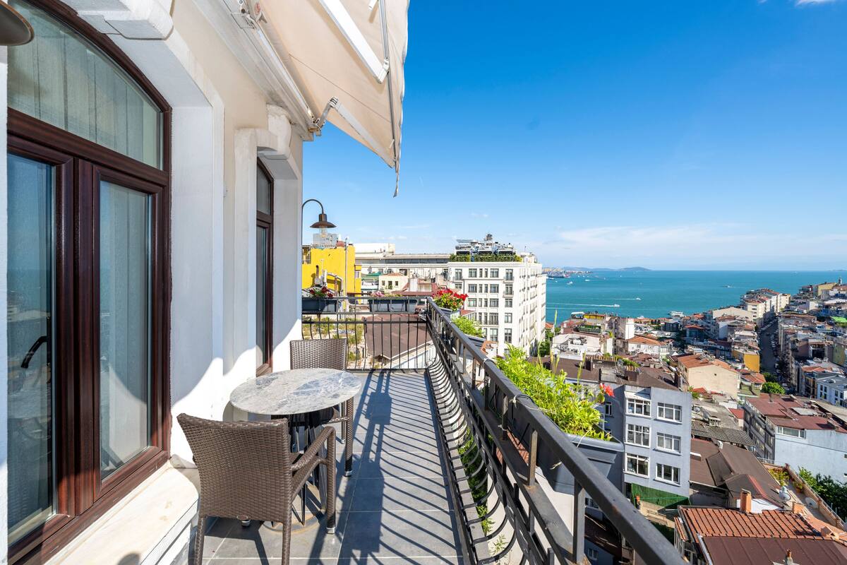 A balcony with wicker furniture and a view of the city and sea.