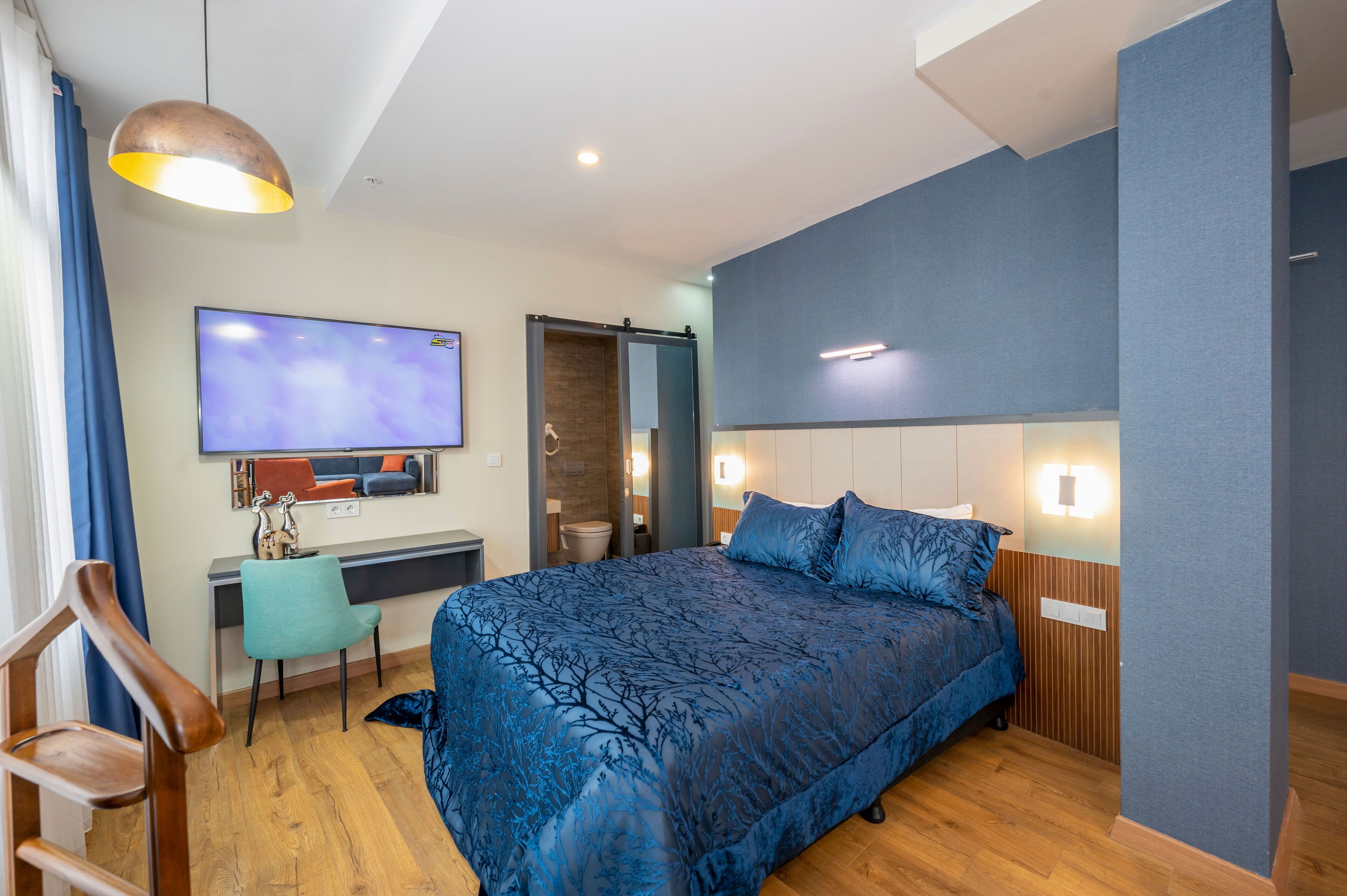 Une chambre moderne avec un grand lit, un bureau, une télévision et une salle de bain.