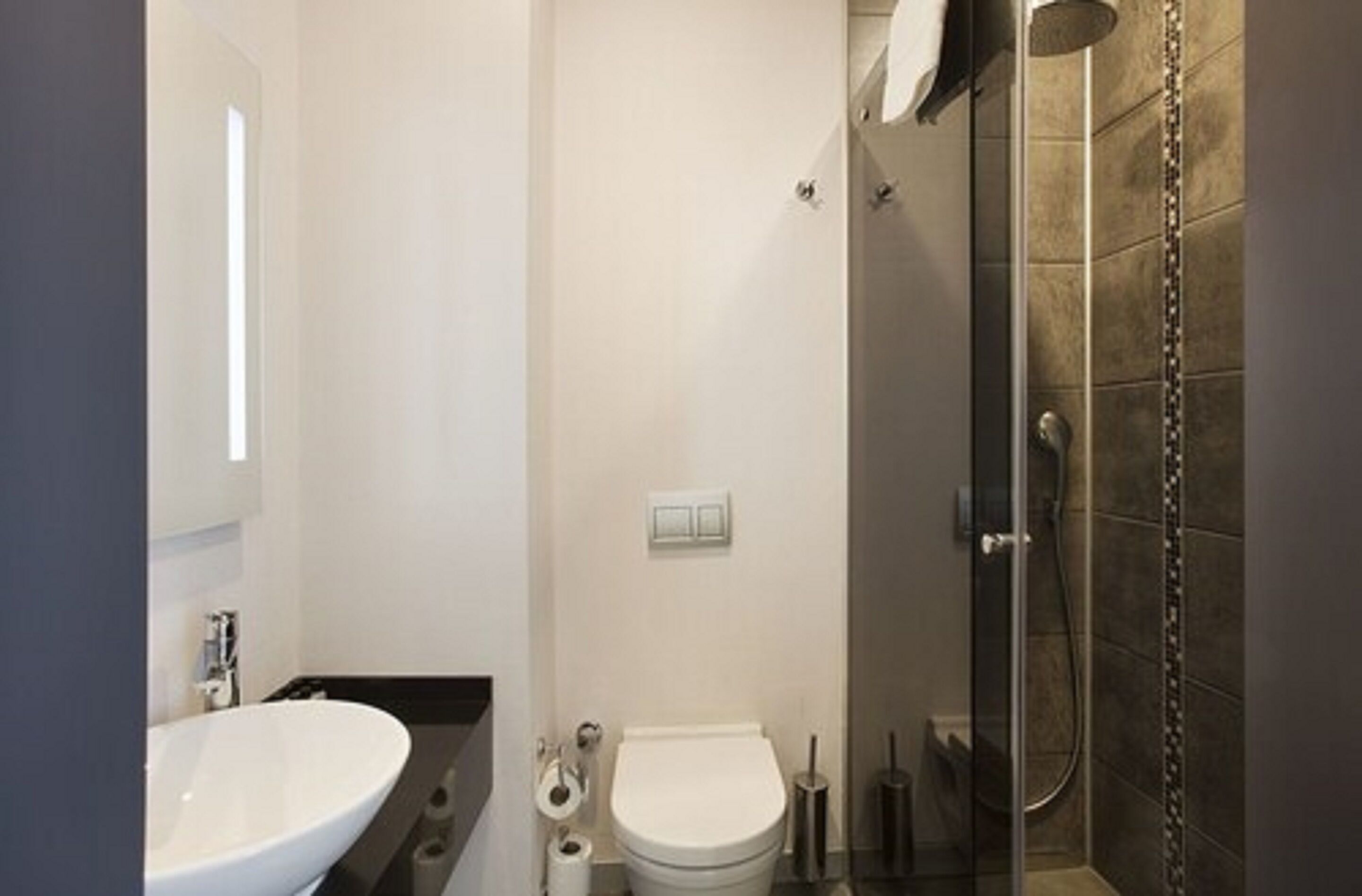 Un bany modern amb un lavabo, vàter i plat de dutxa de color blanc.
