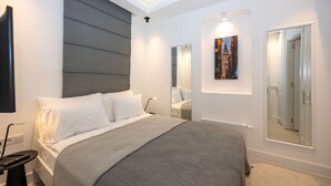 A modern bedroom with a large bed, bedside tables, a mirror, and a painting on the wall. - Juno Hotel Taksim (Istanbul)