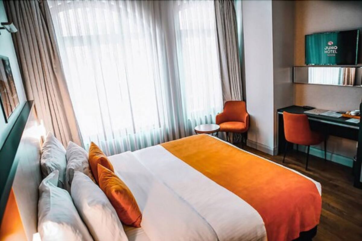A hotel room with a bed, a desk, a chair, and a television on a shelf.