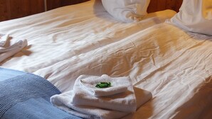 A neatly made bed with a folded towel and a green object on it. - Neðra-Vatnshorn (Hvammstangi)