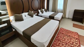 A hotel room with two beds, a ceiling fan, an air conditioner, and a red patterned rug. - Hotel Muskan (Mathura)