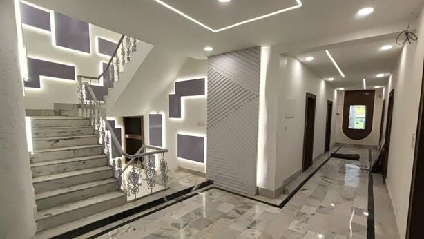 A modern interior with a marble staircase, recessed lighting, and geometric wall designs. - Hotel Muskan (Mathura)