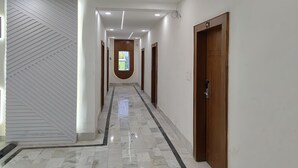 A hallway with a marble floor, recessed lighting, and wooden doors. - Hotel Muskan (Mathura)
