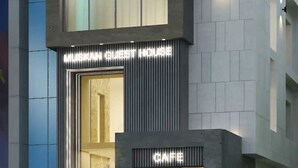 A modern building with a prominent entrance, a cafe area, and a sign indicating a guest house. - Hotel Muskan (Mathura)