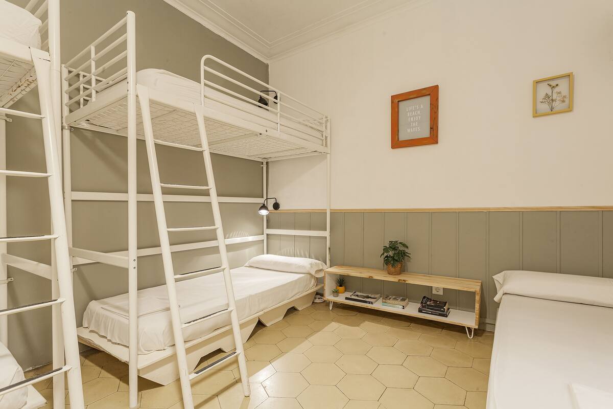 Quarto com beliche, prateleira e quadro com uma frase na parede.