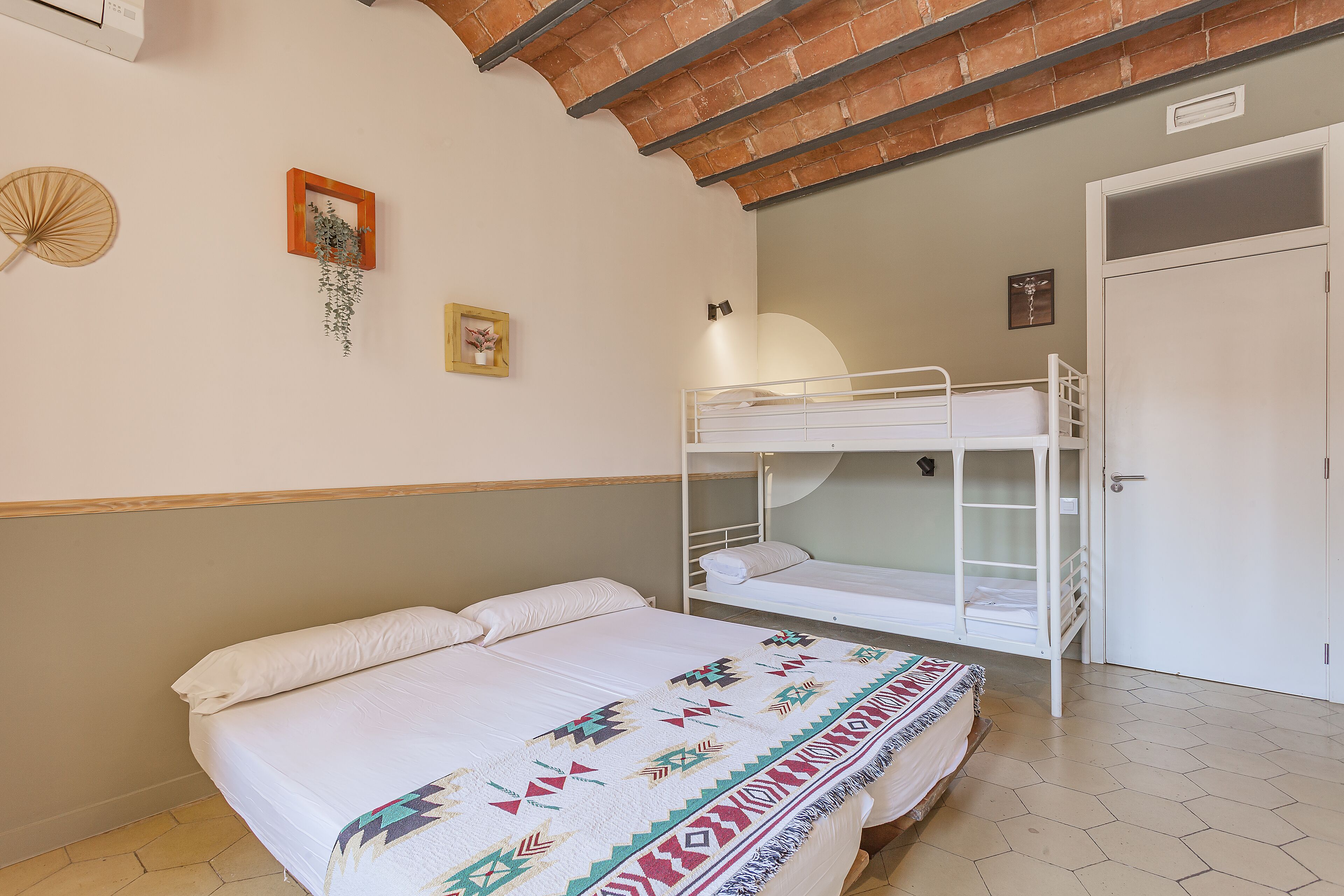 A bedroom with a bunk bed, a single bed, a fan, and a door.