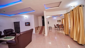 A spacious living area with a sofa, chairs, a staircase, and a dining area. - EEMJM Hotels and Suites Limited (Uyo)