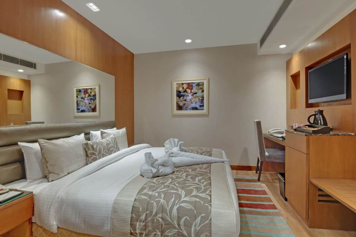 Una camera d'albergo con un letto grande, una scrivania, una televisione e opere d'arte alle pareti.