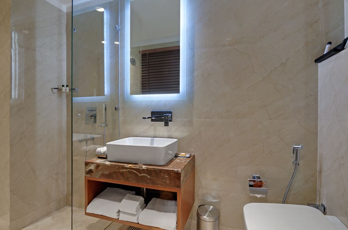 A modern bathroom with a glass-enclosed shower, a marble vanity with a sink, and a large mirror.