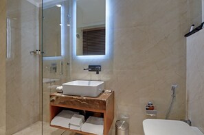 A modern bathroom with a glass-enclosed shower, a marble vanity with a sink, and a large mirror. - Beacon Hotel Nirman Vihar New Delhi (New Delhi)