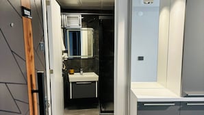 A modern bathroom with a vanity, sink, and mirror. - Inci Konaklama (Isparta)