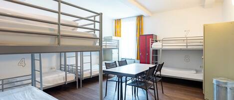 Un dormitorio con literas, una mesa de comedor, sillas y taquillas.