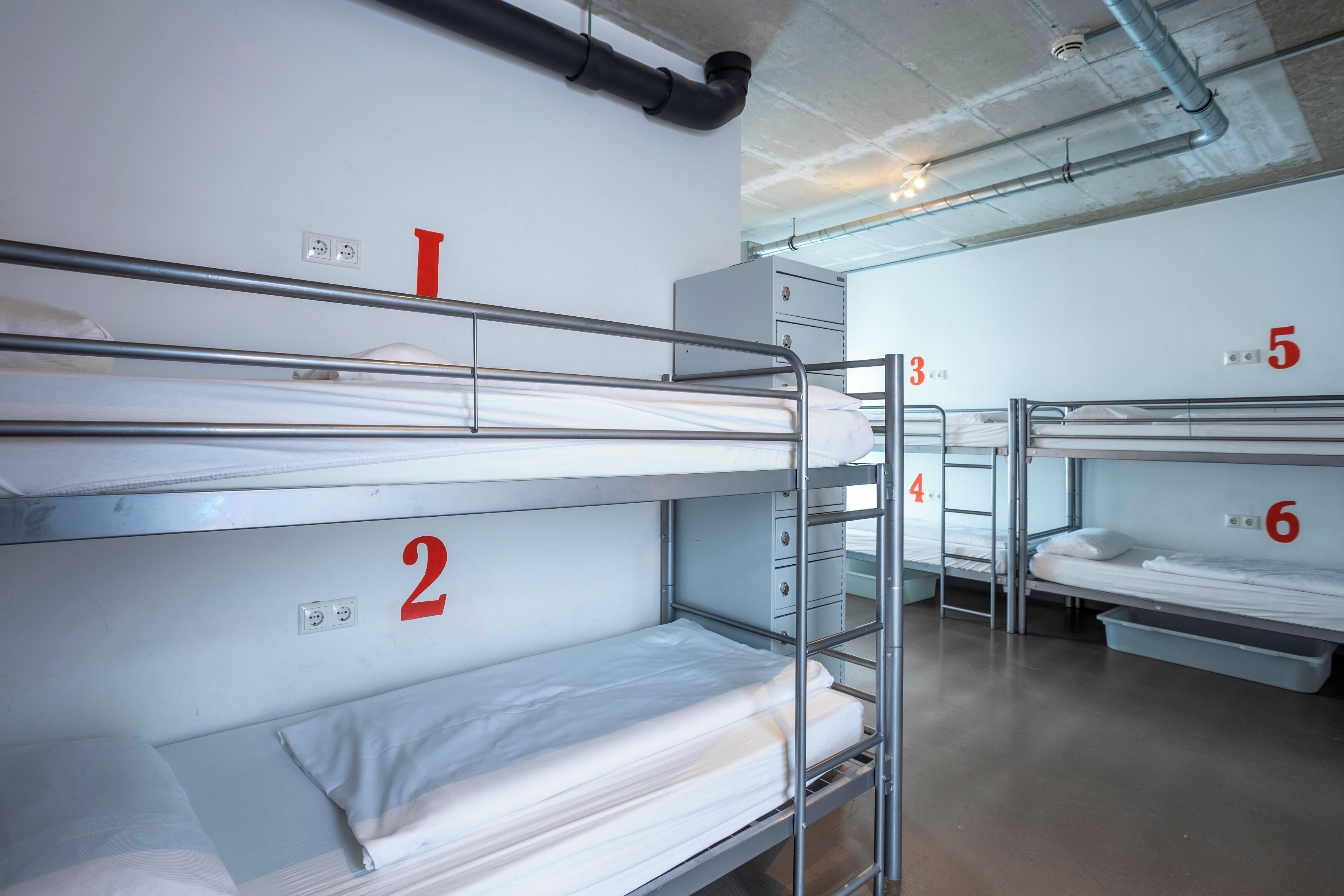 Bunk beds in a dormitory room with numbers on the walls indicating room assignments.