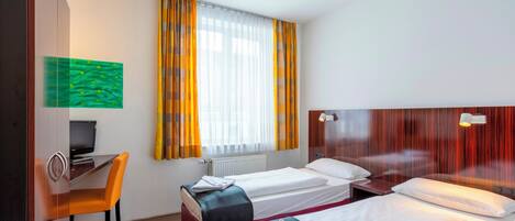 Une chambre d’hôtel avec deux lits, un bureau et une chaise.