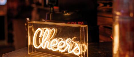 A neon sign with the word "Cheers" in a bar setting.