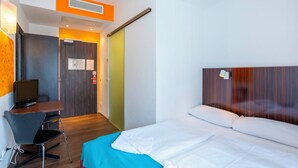 A hotel room with a bed, a desk with a computer, and a chair. - Jaeger's Munich - Hostel (Munich)
