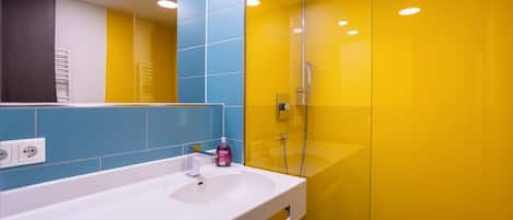 A modern bathroom with a white sink, a mirror, and a shower area.