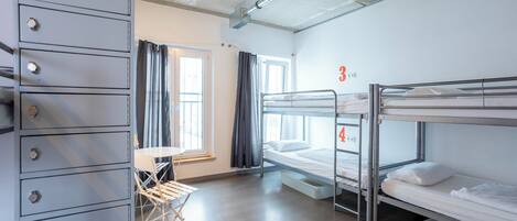 A dormitory room with bunk beds, a desk, and a storage cabinet.