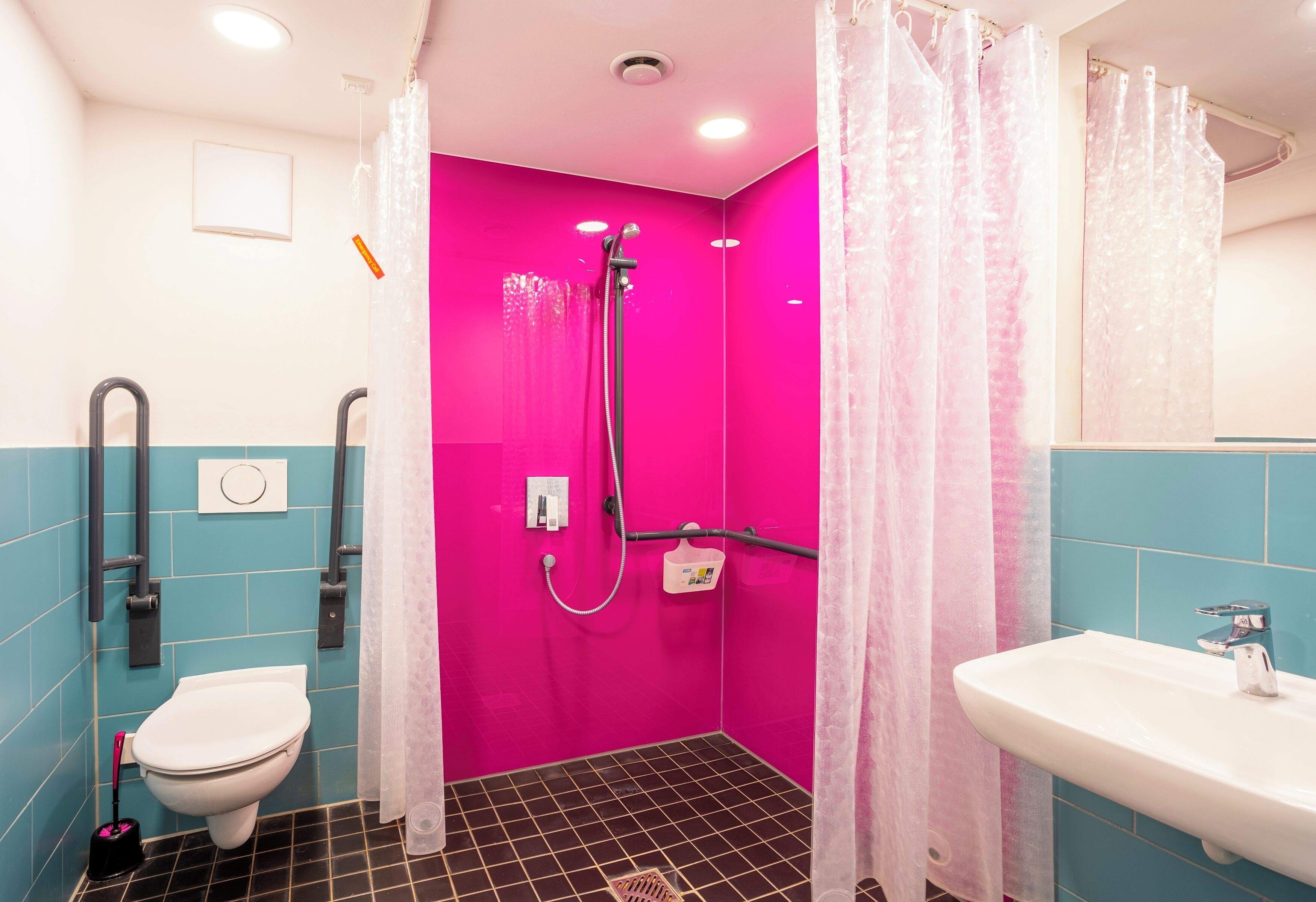A bathroom with a pink shower, a white toilet, and a sink.