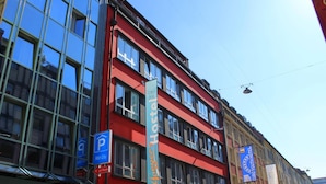A red building with large windows and a blue sign for Jaegers Hotel. - Jaeger's Munich - Hostel (Munich)