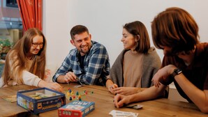 A group of people playing a board game at a wooden table. - Jaeger's Munich - Hostel (Munich)