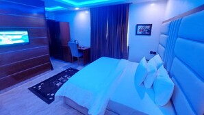 A modern hotel room with a large bed, a desk, and a TV mounted on the wall. - NEW POINT HOTEL AND SUITES (Uyo)