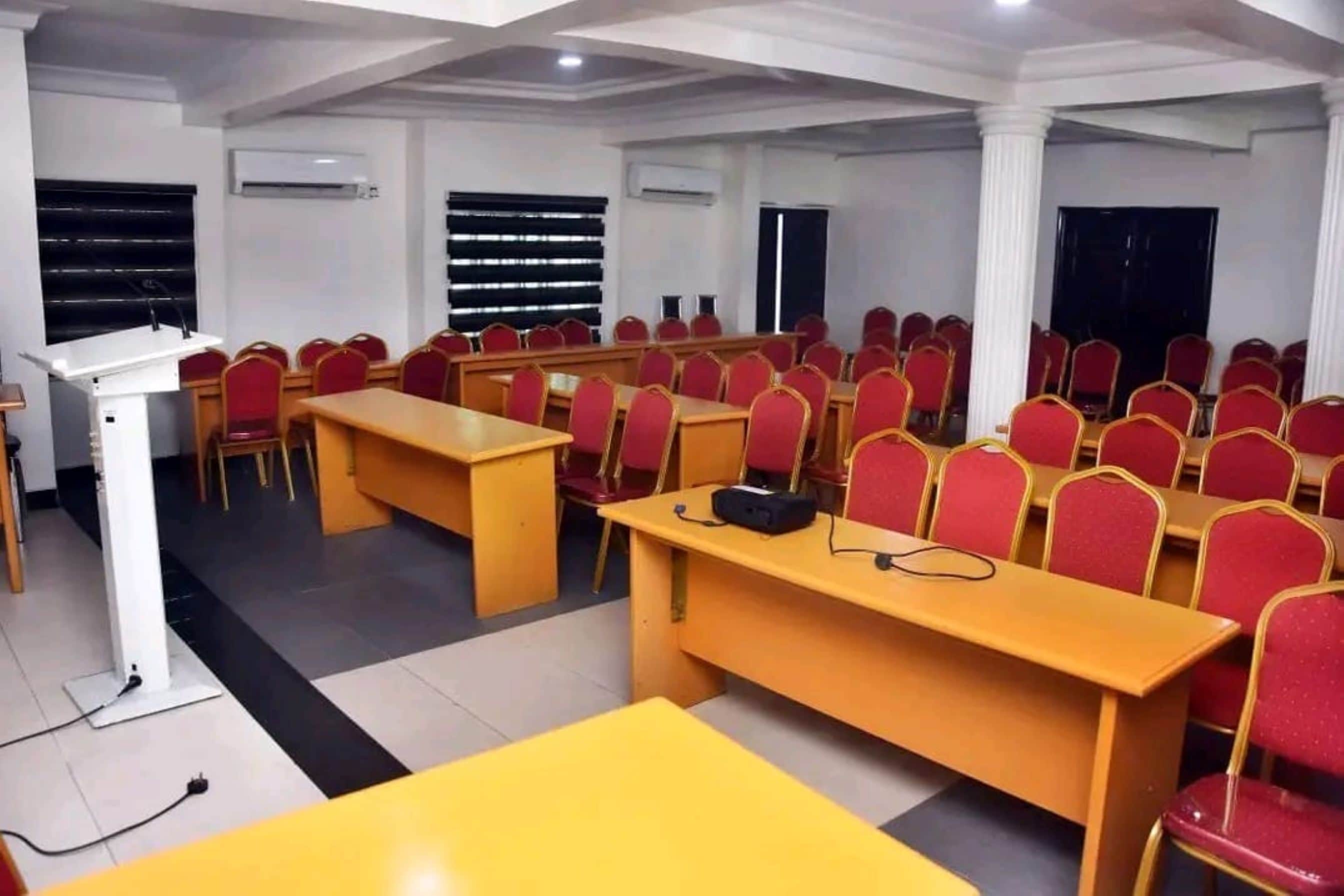 A conference room with rows of red chairs, a podium, and tables.