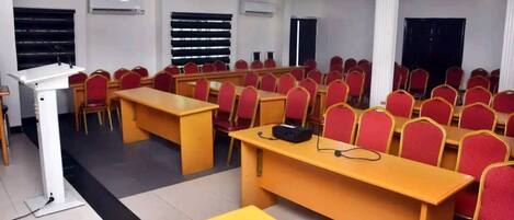 A conference room with rows of red chairs, a podium, and tables.
